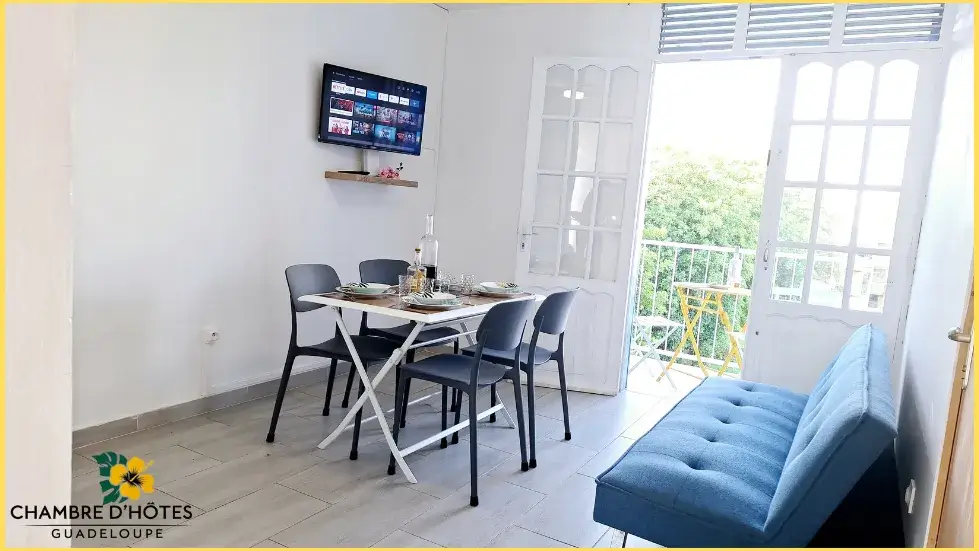 Espace partagé salon et salle à manger lumineux avec accès au balcon et vue sur espace vert pour nos invités aux Chambres d'hôtes Carnaval aux Abymes