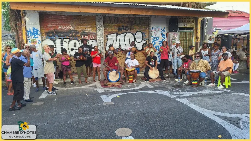 Groupe de musiciens traditionnels jouant du tambour Ka et chantant du Gwo Ka dans une rue piétonne animée près de la place Marcel Lollia, (Vélo) au cœur de l'ambiance guadeloupéenne