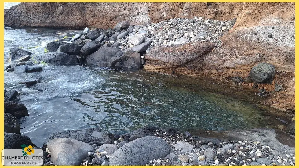 Détente dans le bassin naturel du Bain Thomas, une source d'eau chaude se déversant directement dans la mer à Bouillante en Guadeloupe
