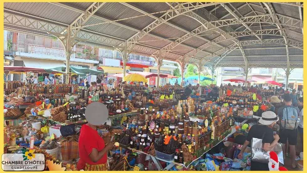Alignement coloré de bouteilles de punchs, liqueurs artisanales et sachets d'épices sur un stand du marché Saint-Antoine