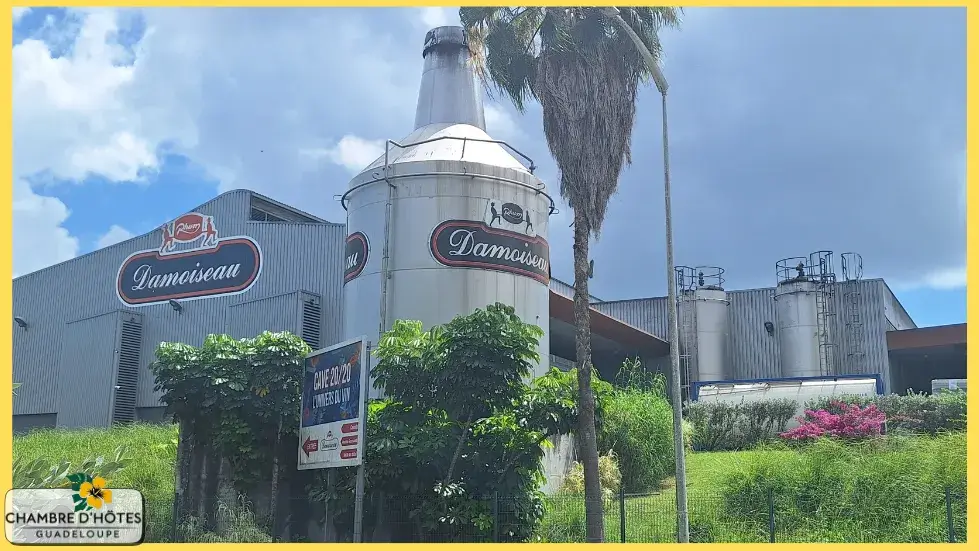 Espace visiteur à l'arrière de l'usine Damoiseau mettant en scène le patrimoine industriel avec un ancien alambic, une bouteille géante et l'accès aux chais